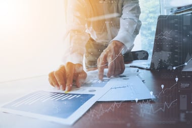 Business documents on office table with smart phone and digital tablet and graph financial with social network diagram and man working in the background